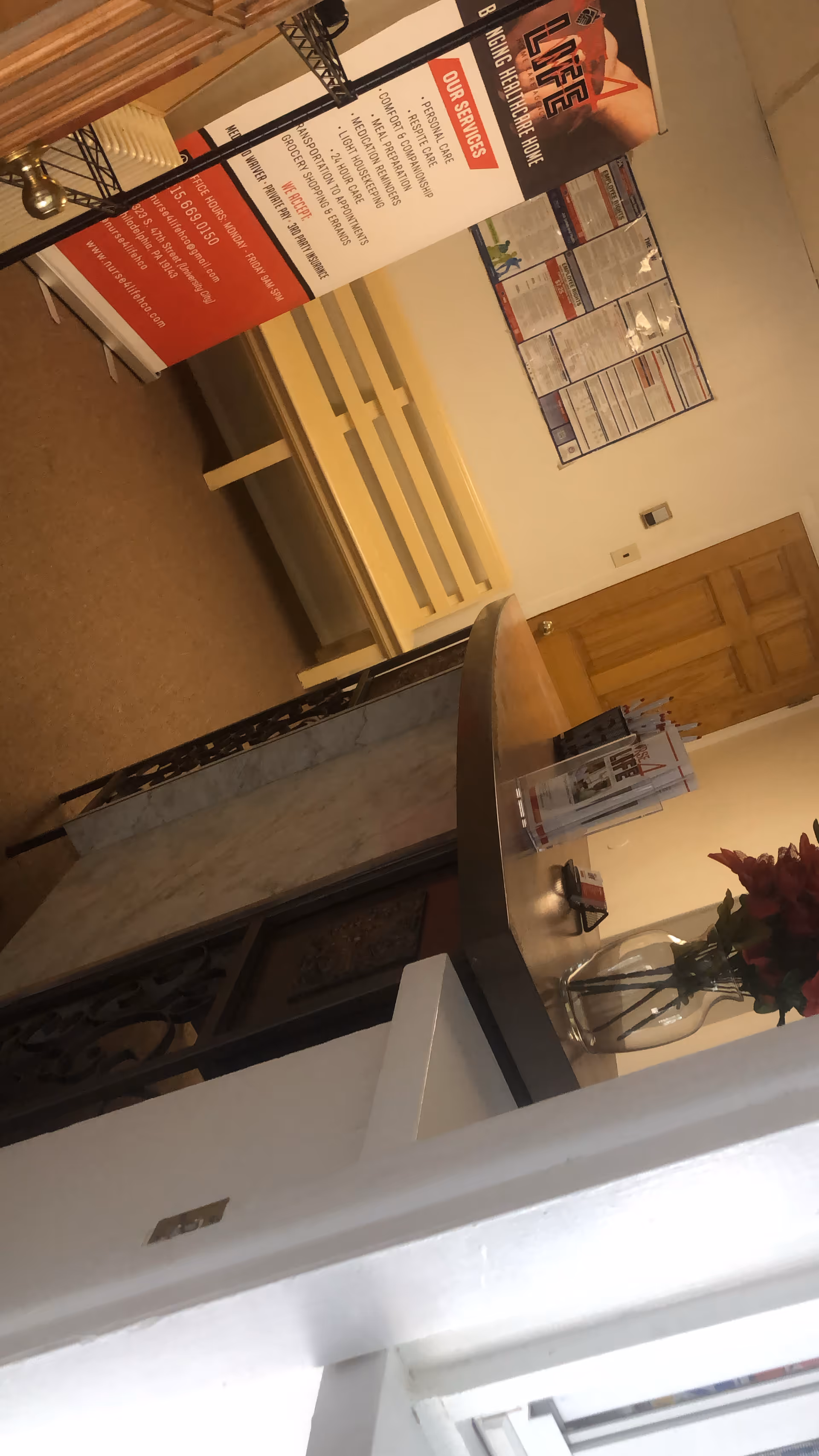 Indoor reception area of a senior care facility with a curved counter and brochure stand.