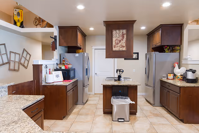 A spacious kitchen with central island, dark wood cabinets, and stainless appliances.