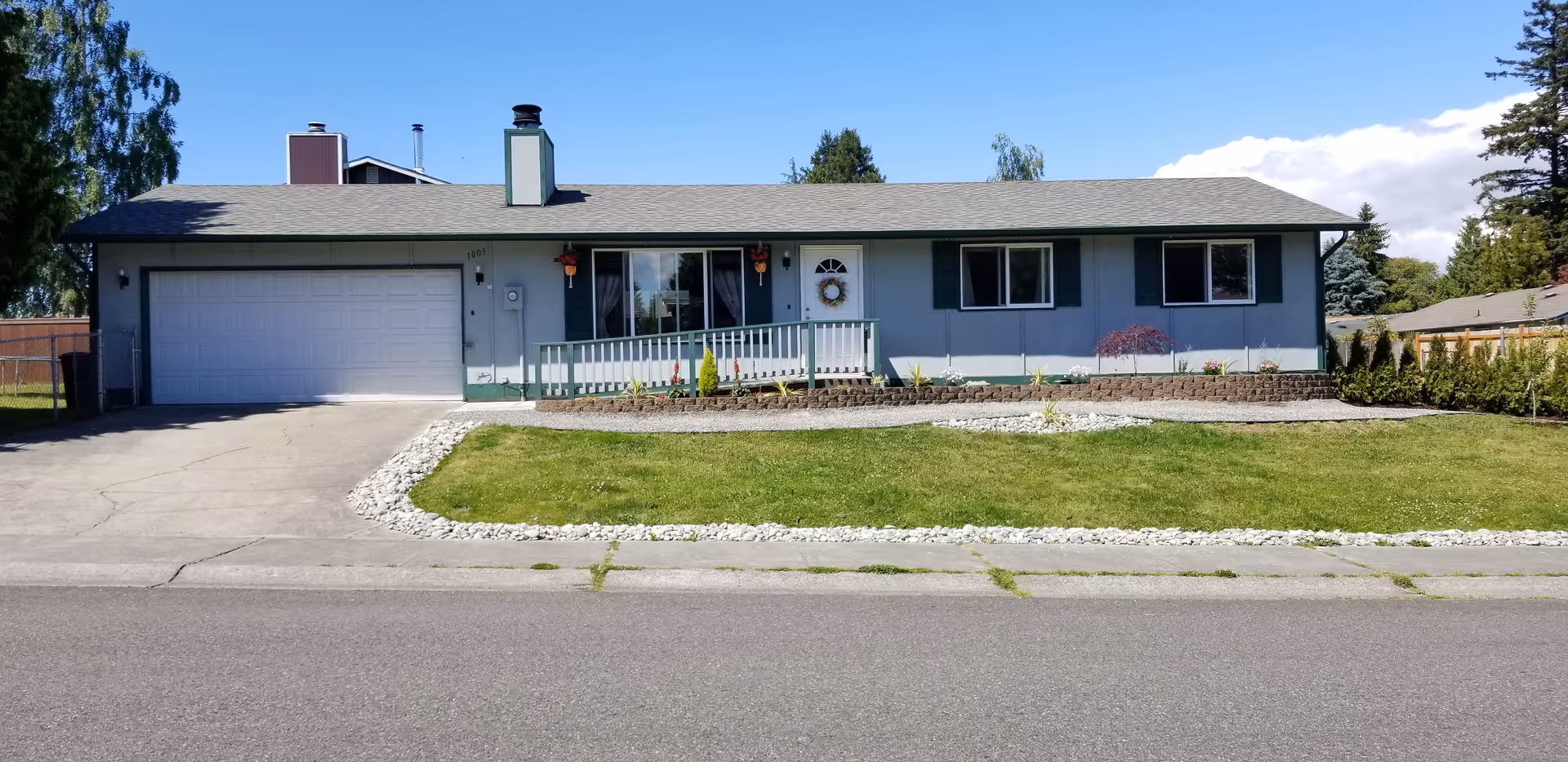 Blue single-story house with a two-car garage, front porch, and lawn.