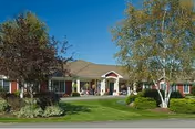 Front view of a single-story senior living facility with lawn and welcoming entrance.