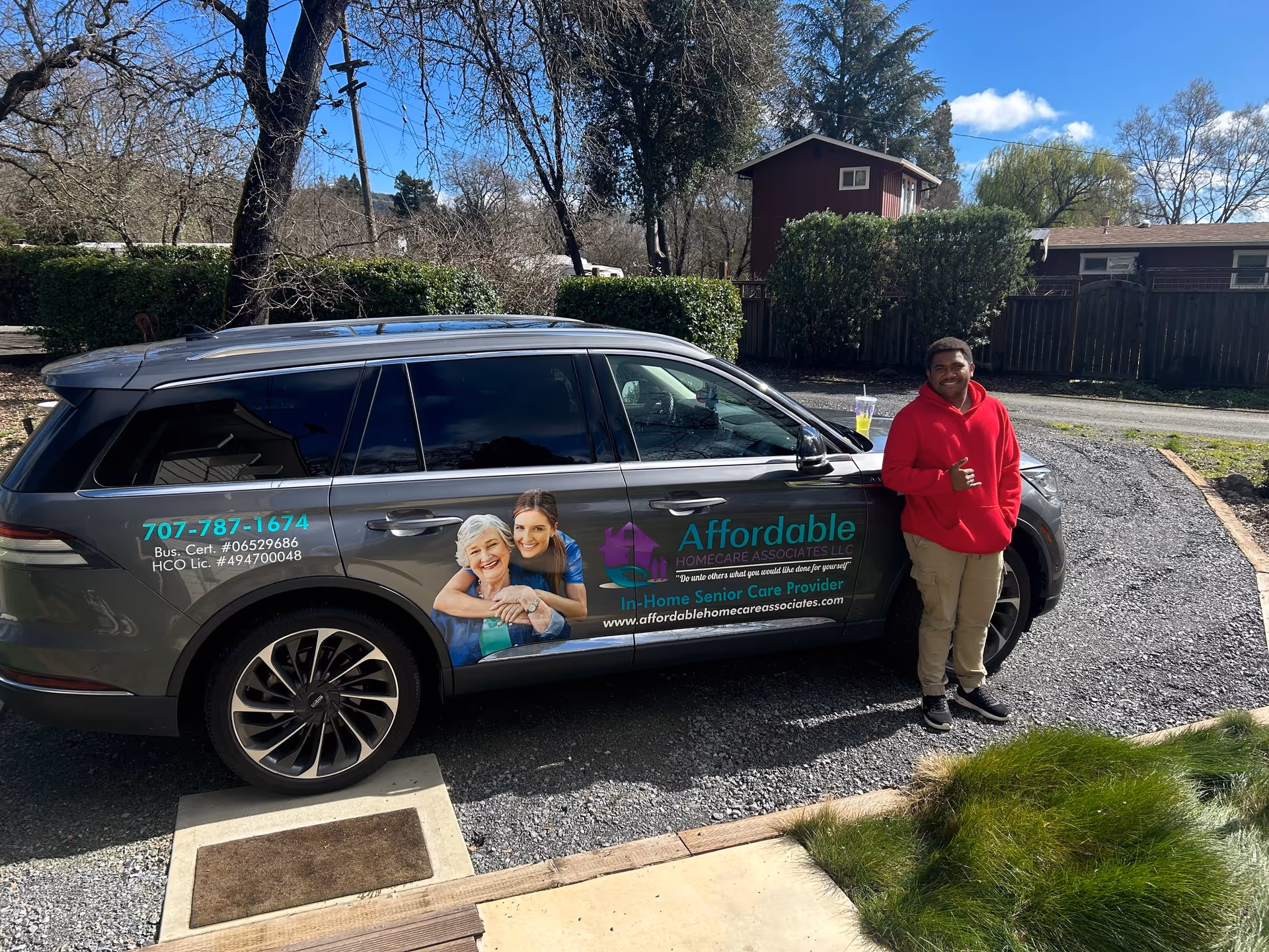 Caregiver in red hoodie stands beside a branded Affordable Homecare van.