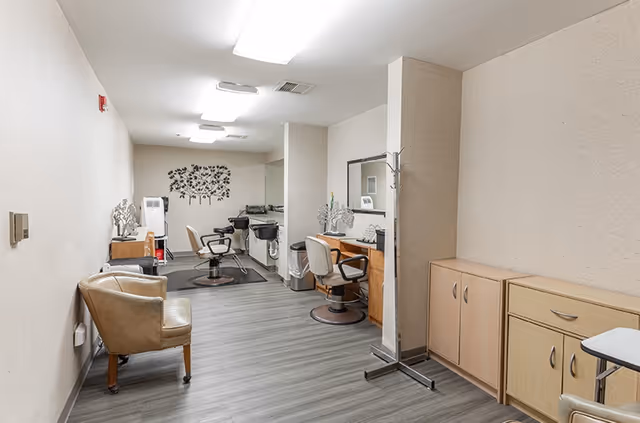 Interior corridor featuring a salon area with chairs, mirrors, and cabinets.