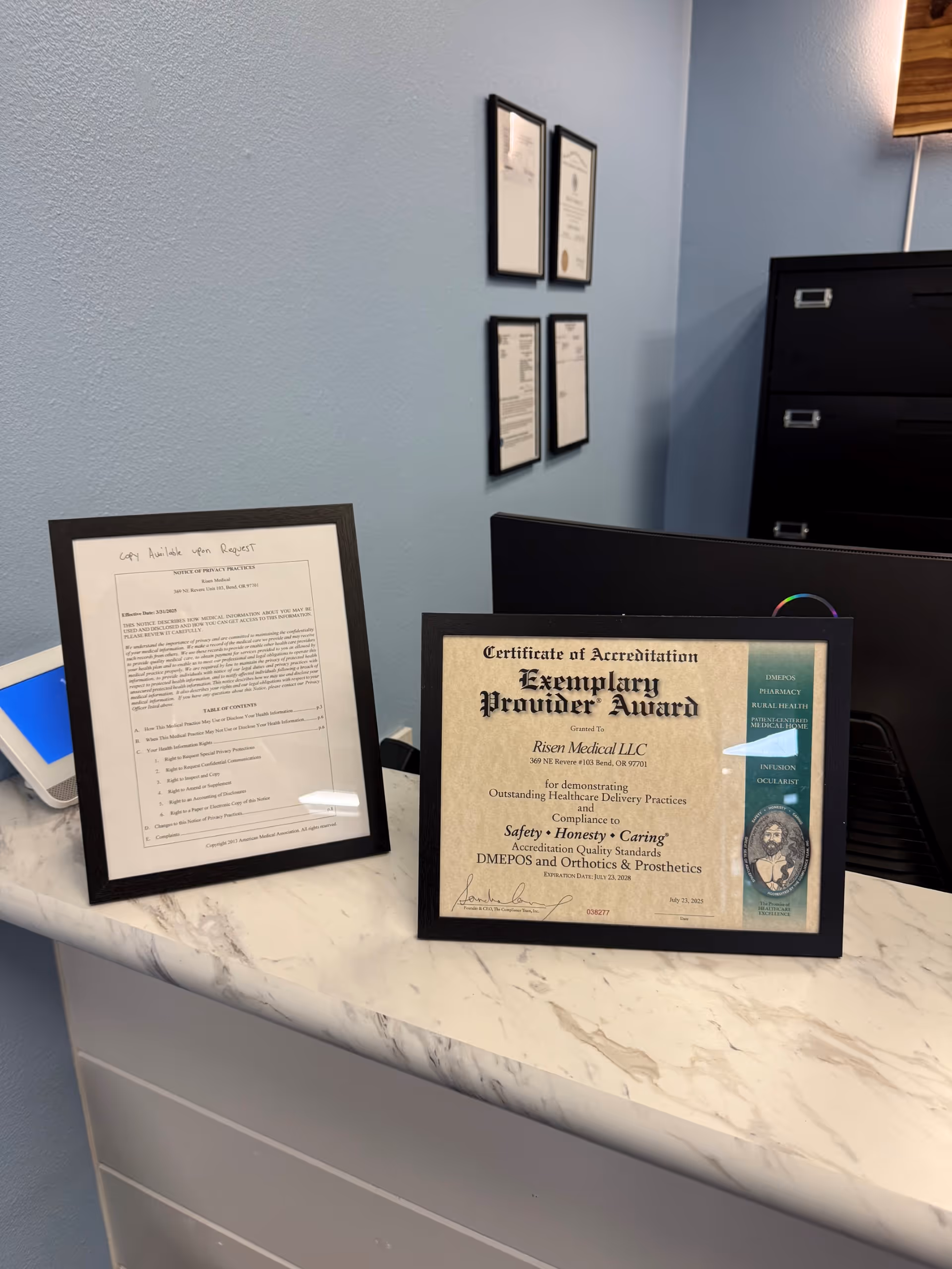 Blue-walled reception area with framed certificates on a marble countertop.