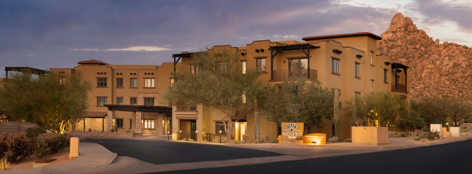 Front exterior of ACOYA Troon senior living with desert landscaping and mountains.