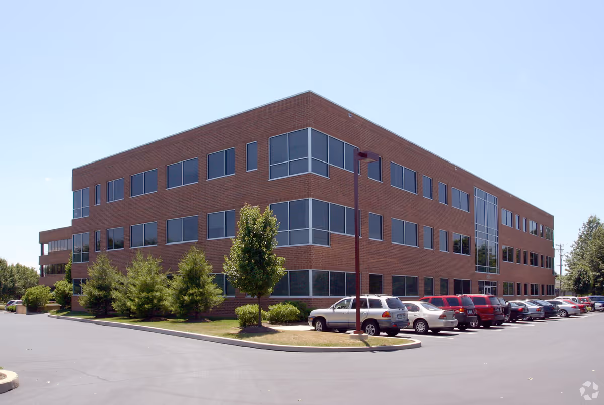 Three-story brick senior living facility exterior with many windows and a parking lot.