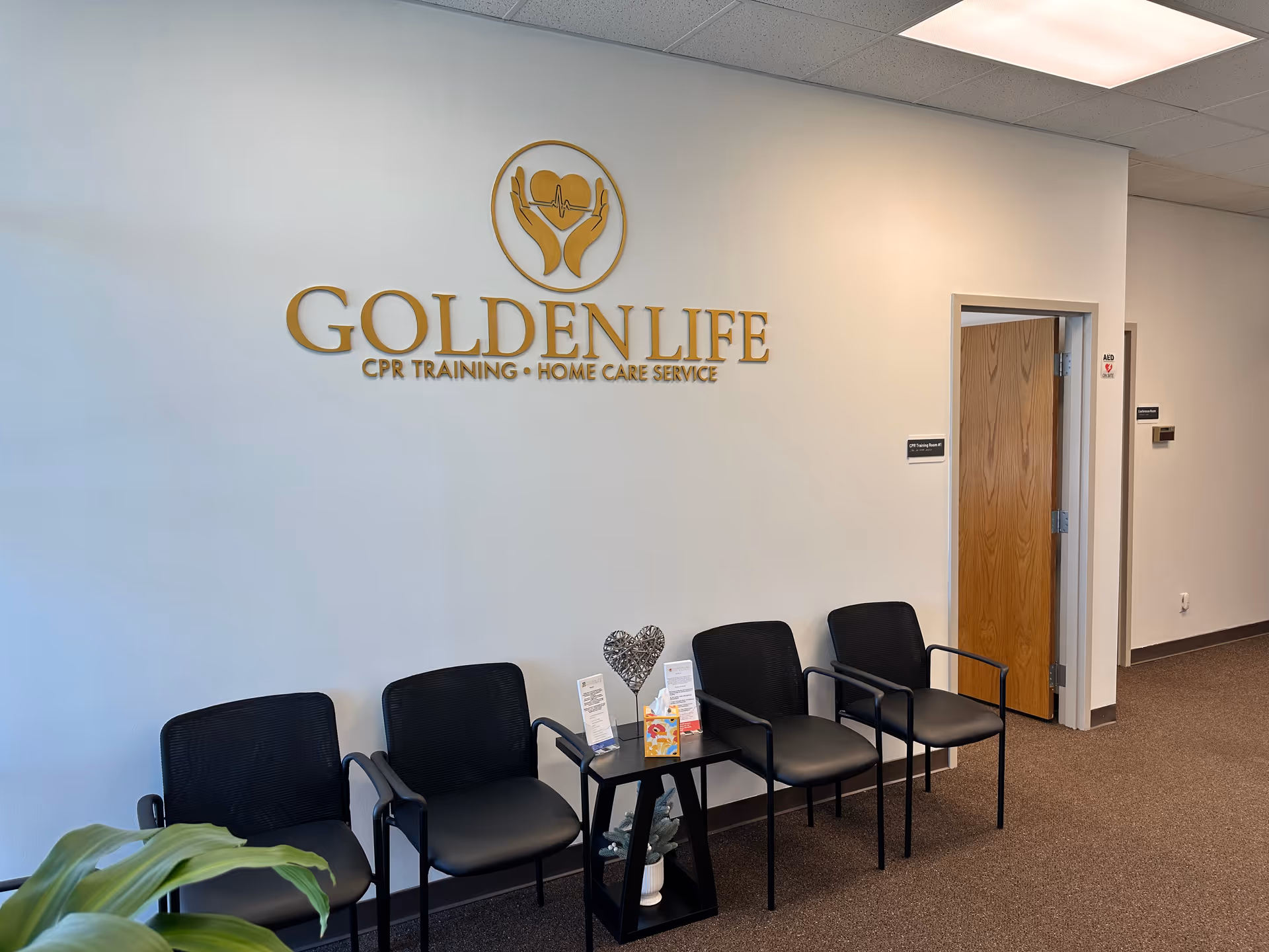 Lobby seating area with five black chairs and Golden Life logo on the wall.