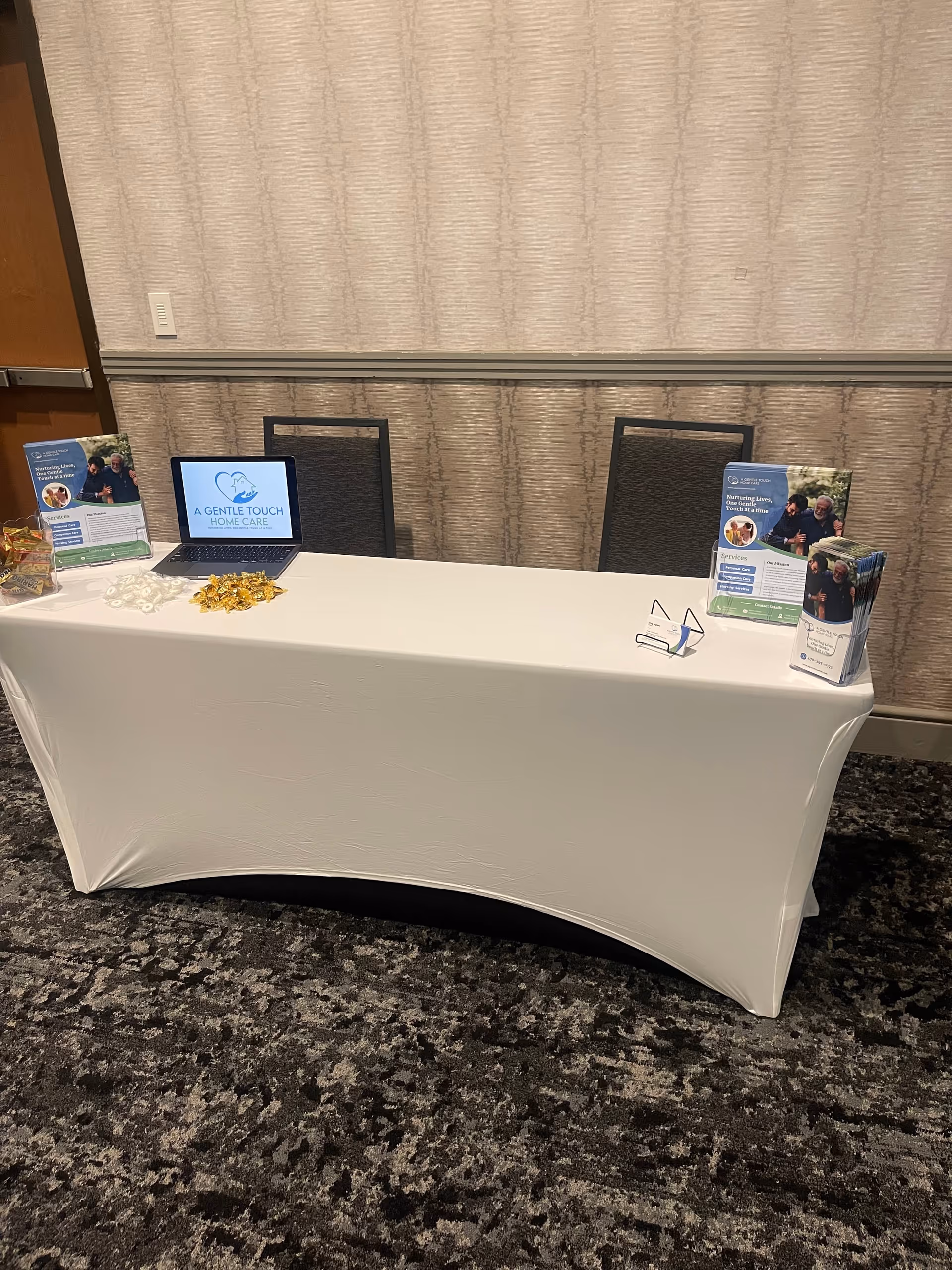 A table setup with brochures and a laptop displaying A Gentle Touch Home Care.