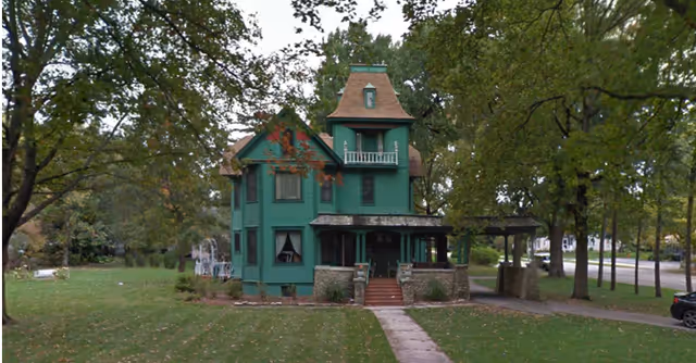 Exterior view of Robin's Nest, a green house-shaped senior living building.