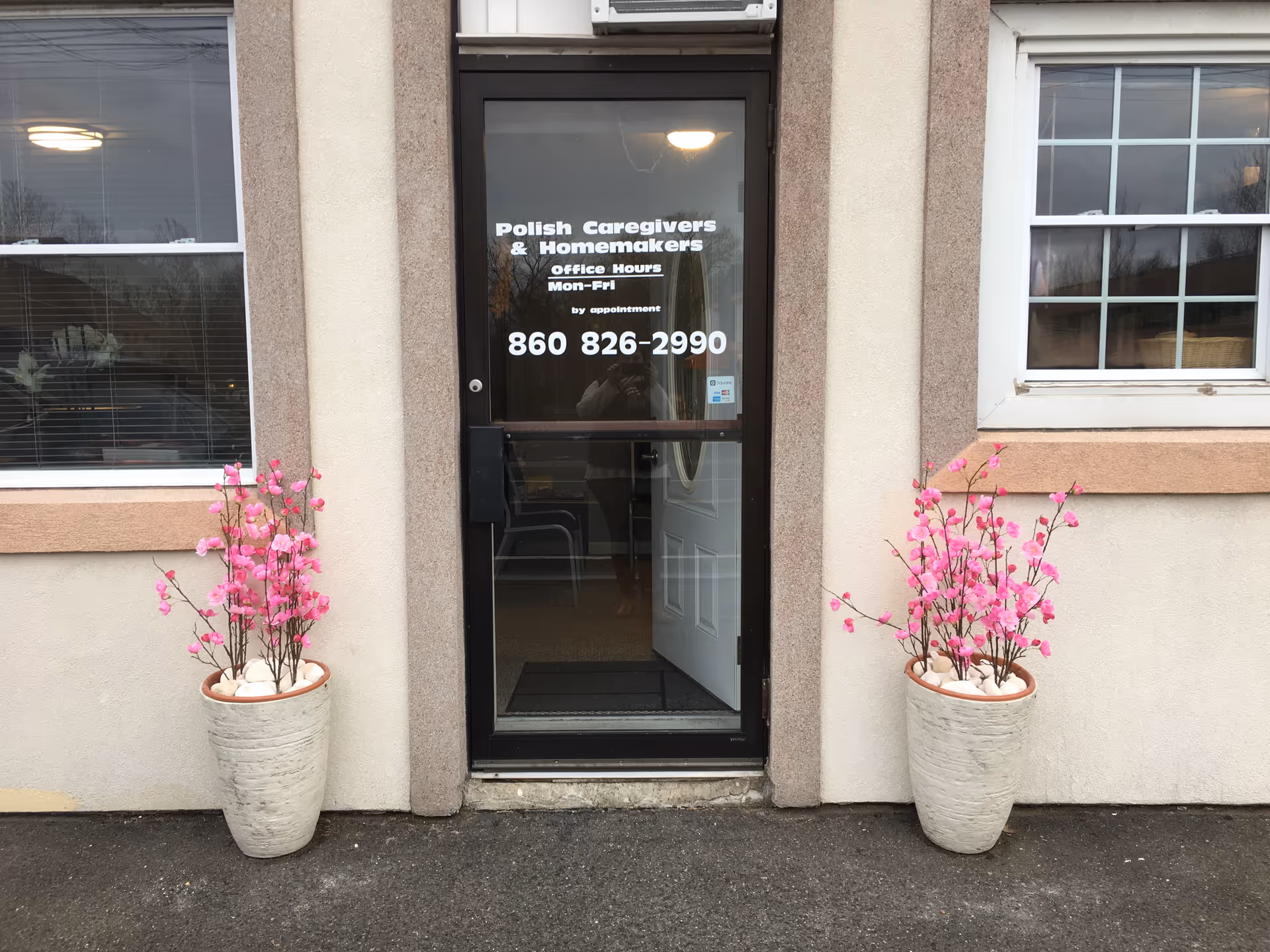 Front entrance of Polish Caregivers & Homemakers building with pink potted flowers.