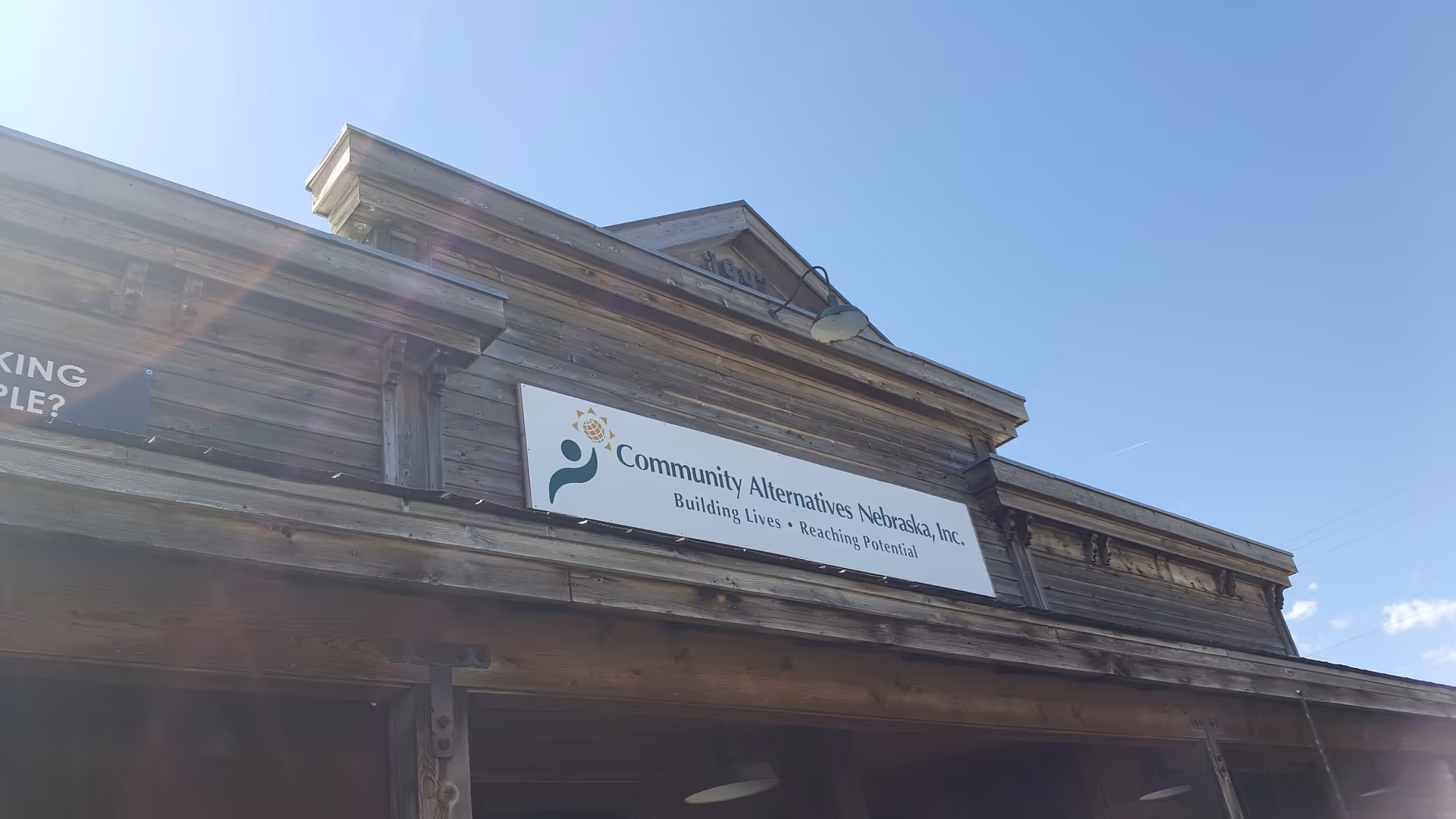 Weathered wooden building facade with a sign for Community Alternatives Nebraska, Inc.