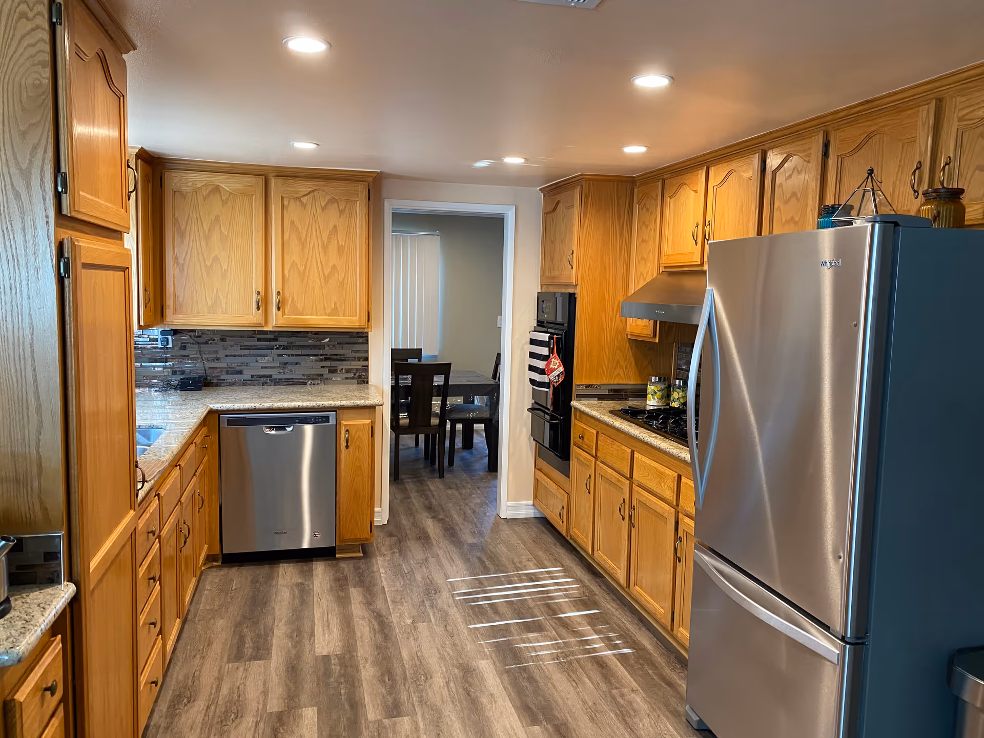 Bright kitchen with wooden cabinets, stainless steel appliances, and a doorway to a dining area.