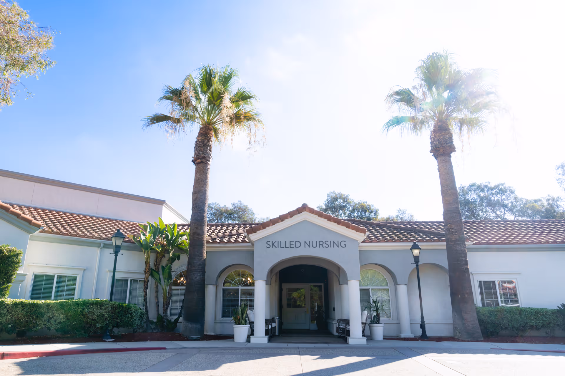 Front entrance of Bayshire San Dimas with palm trees and Skilled Nursing sign.