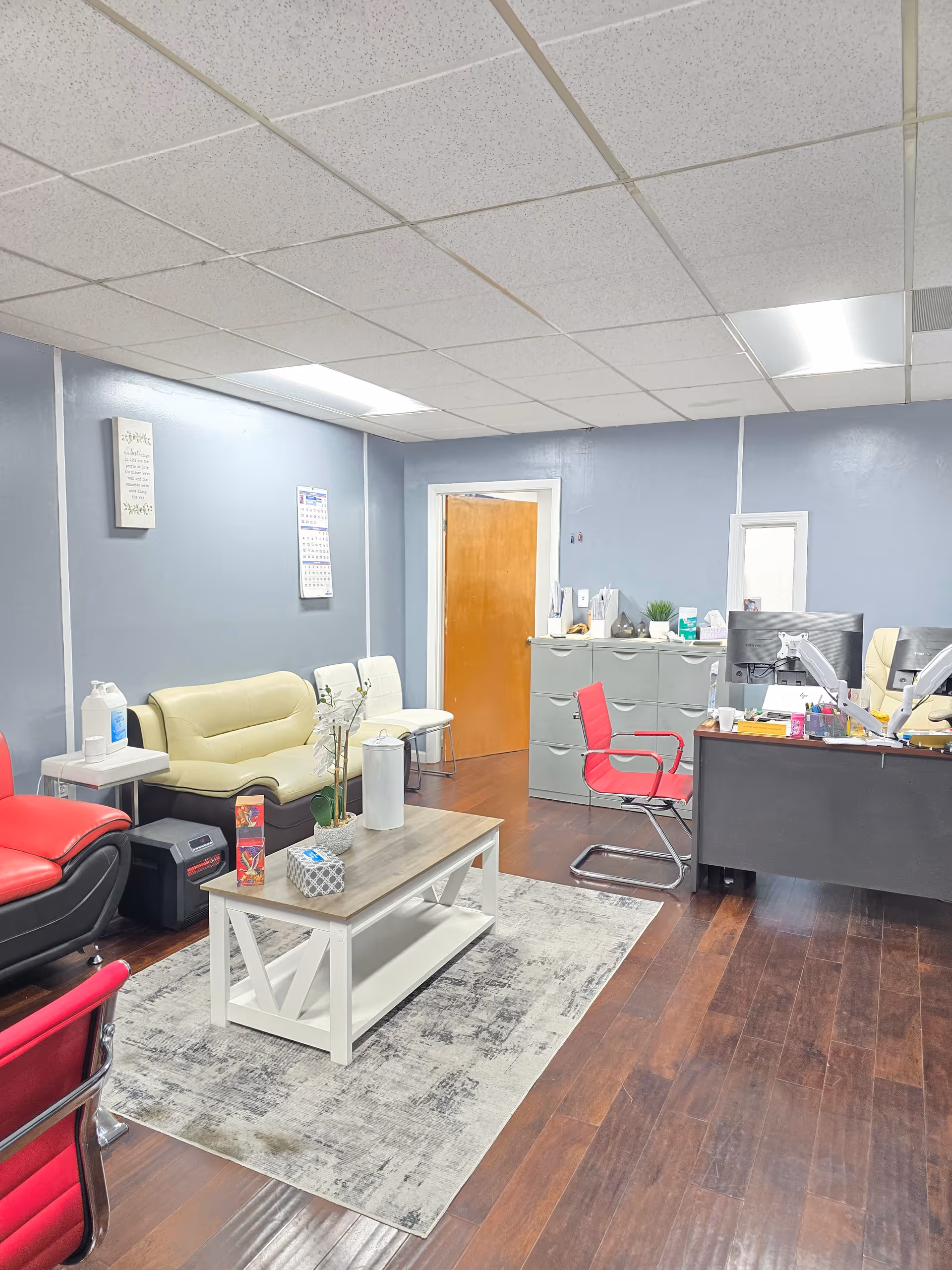 A reception area and lounge with desks, chairs, and a coffee table inside a blue-walled office.