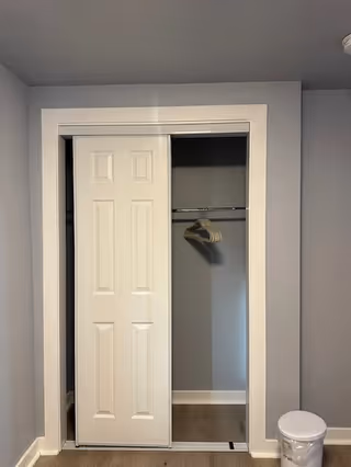 Closet interior with a hanging rod and hangers in a gray room