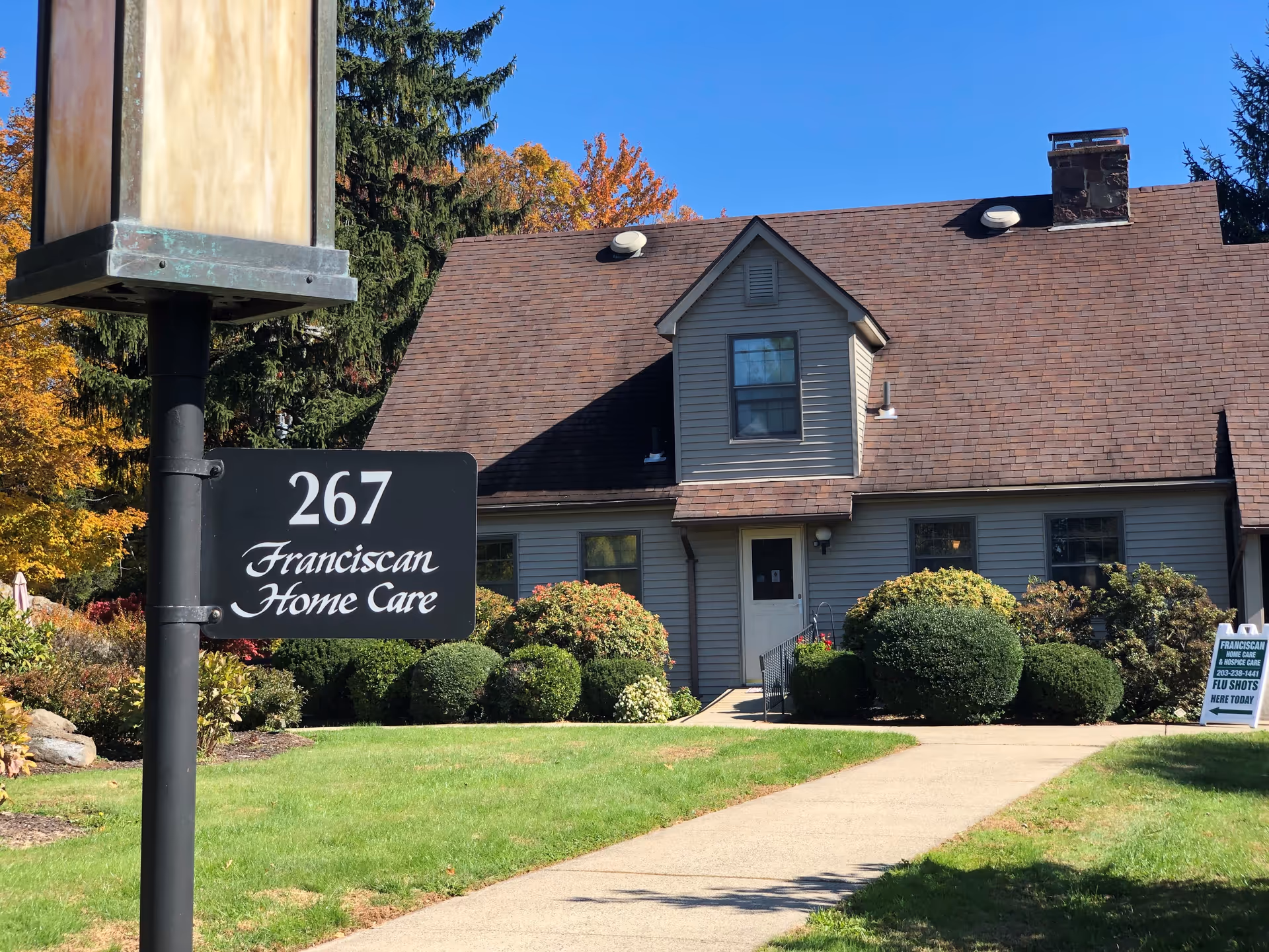 Exterior view of a building with a 267 Franciscan Home Care sign and landscaped front yard