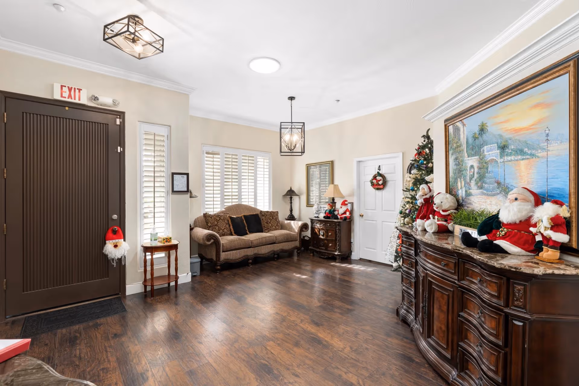 A warmly decorated assisted living lobby with a sofa, front door, wooden sideboards and Christmas decorations.