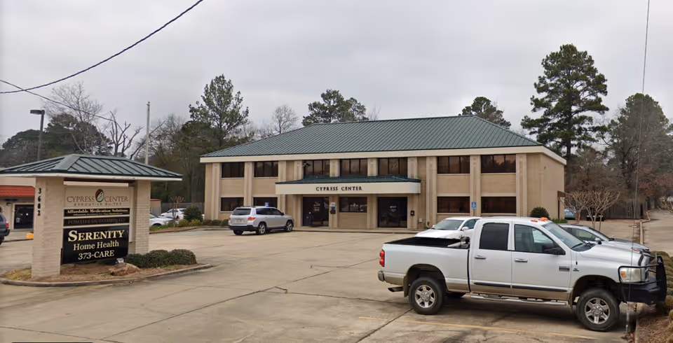 Exterior view of Serenity Home Health center with sign, parking lot, and trees.