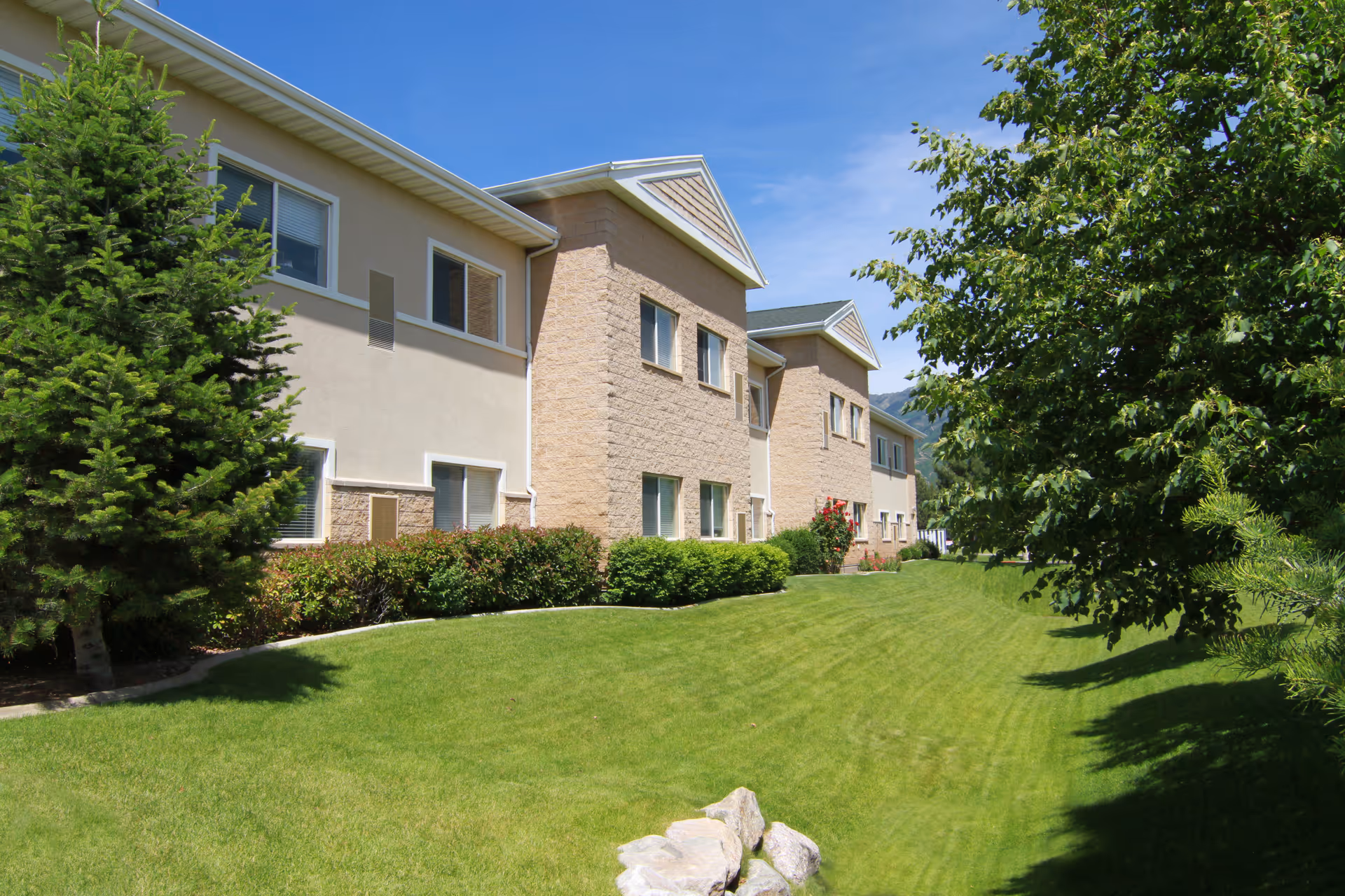 Exterior view of Legacy House Assisted Living of Ogden with green lawn and trees.