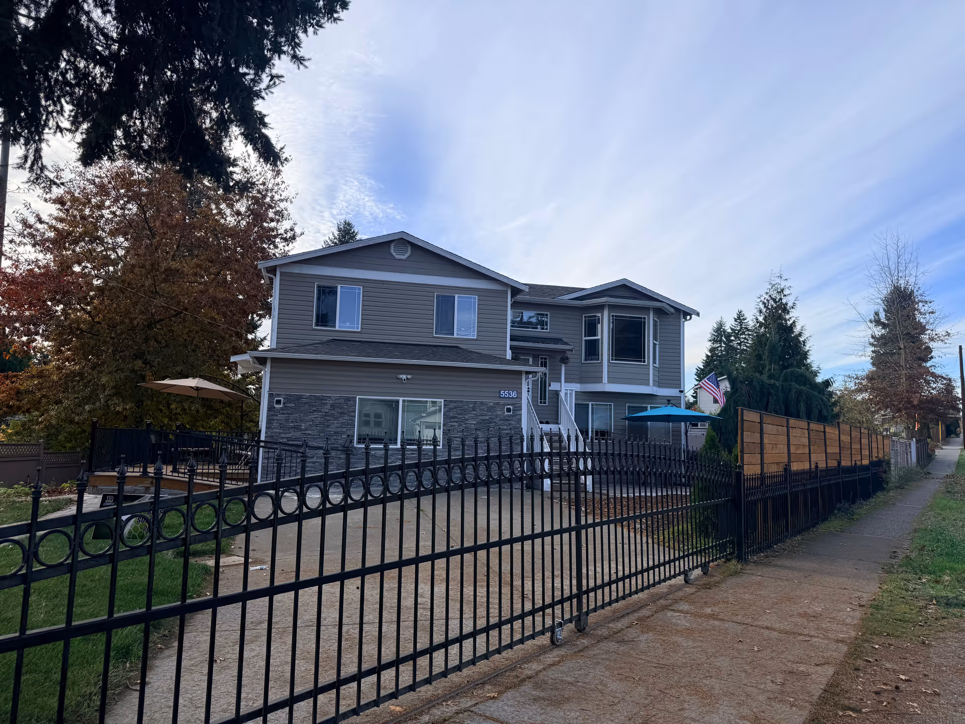 Front exterior of a two-story building with a black wrought-iron fence.