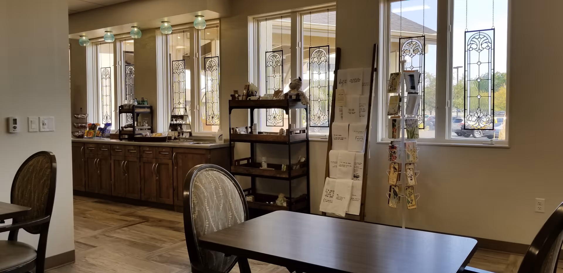 Interior dining area with tables, chairs, and a serving counter by decorative windows.