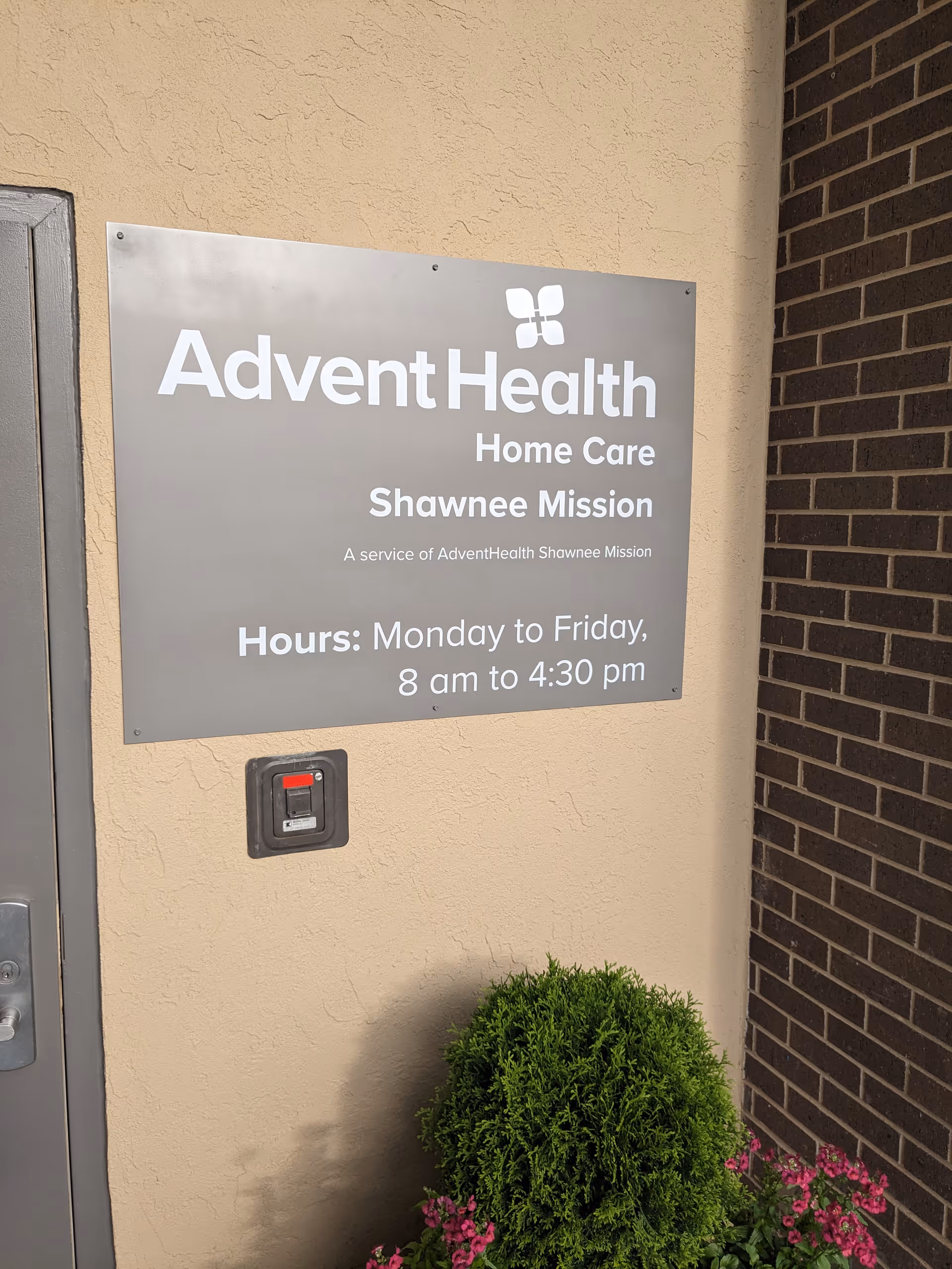 Exterior view of AdventHealth Home Care Shawnee Mission sign on building front with plants