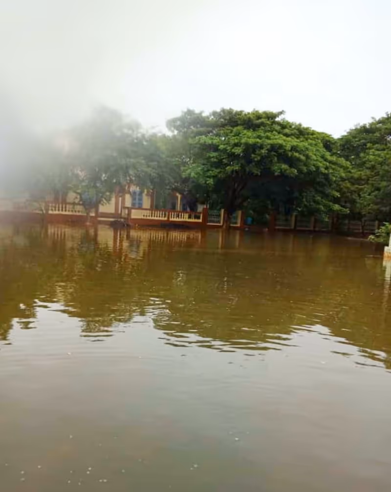 Flooded exterior of a facility, with water rising near the front porch and trees.