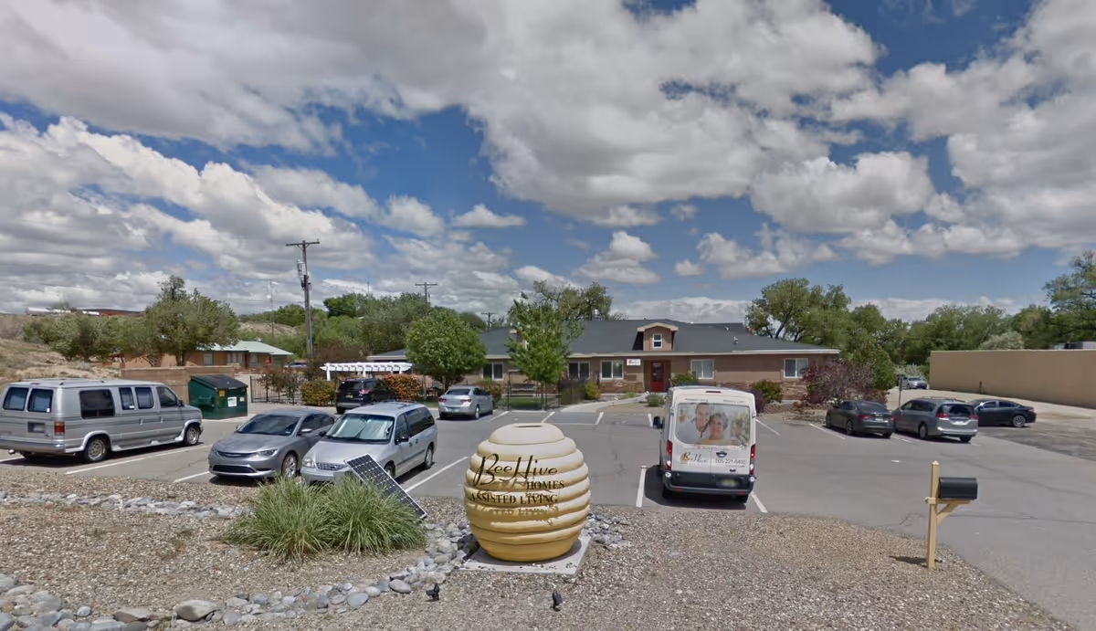 Front view of BeeHive Homes of Farmington with parked cars and desert landscaping