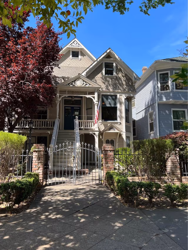 Victorian-style house front with gated entry and landscaped walkway.