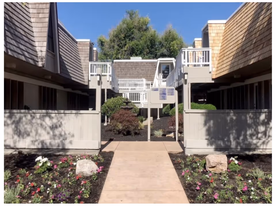 Exterior view of a senior living facility courtyard with walkways, balconies, and landscaped garden.