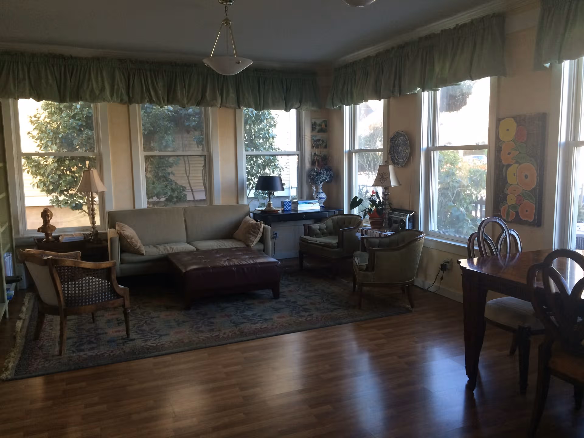 Cozy living room with sofa, chairs, rug, lamps, and large windows.