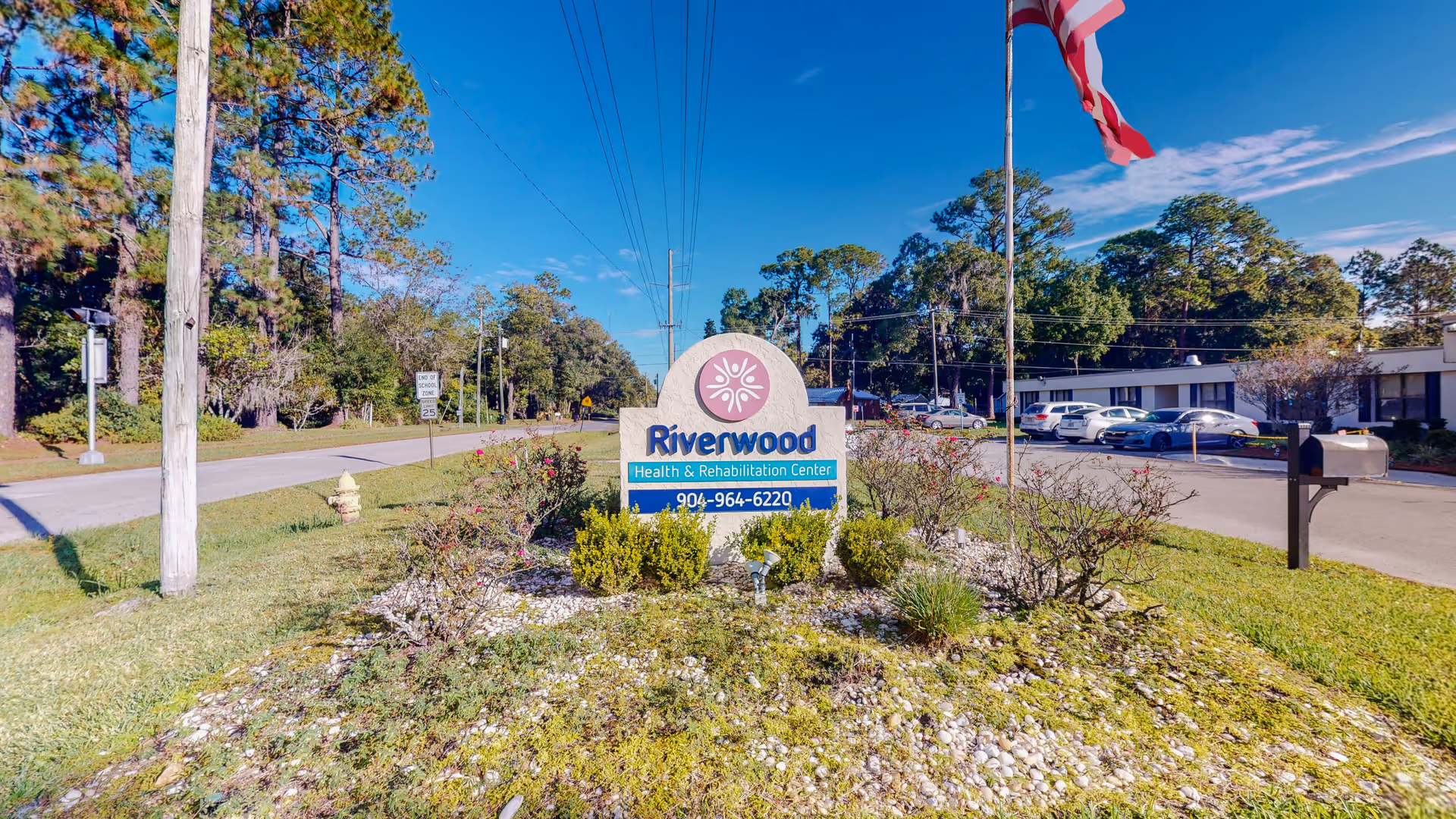 Outdoor view of Riverwood Health and Rehabilitation Center entrance with sign and parking.