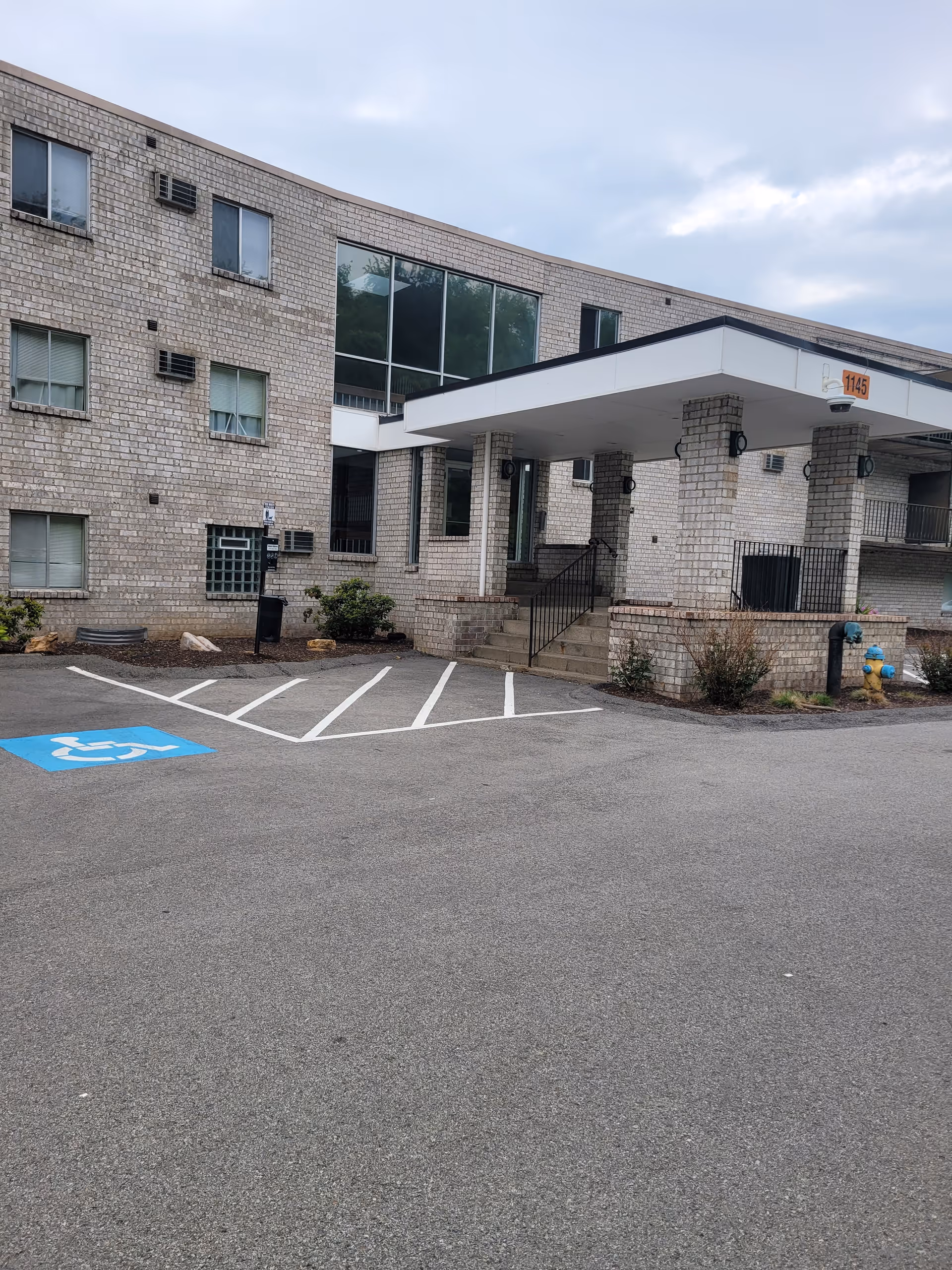 Brick senior living facility with a covered entrance and handicap parking in front