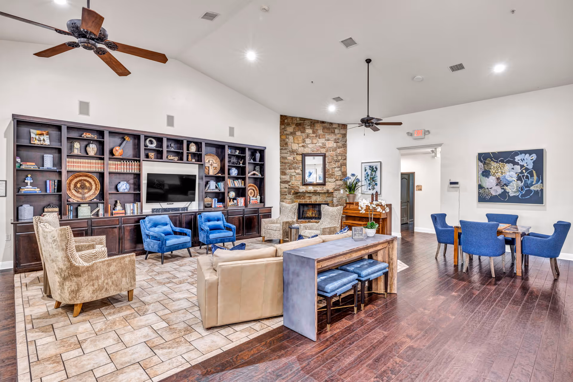 Spacious living room with a built-in bookshelf wall, fireplace, blue chairs, and dining area.