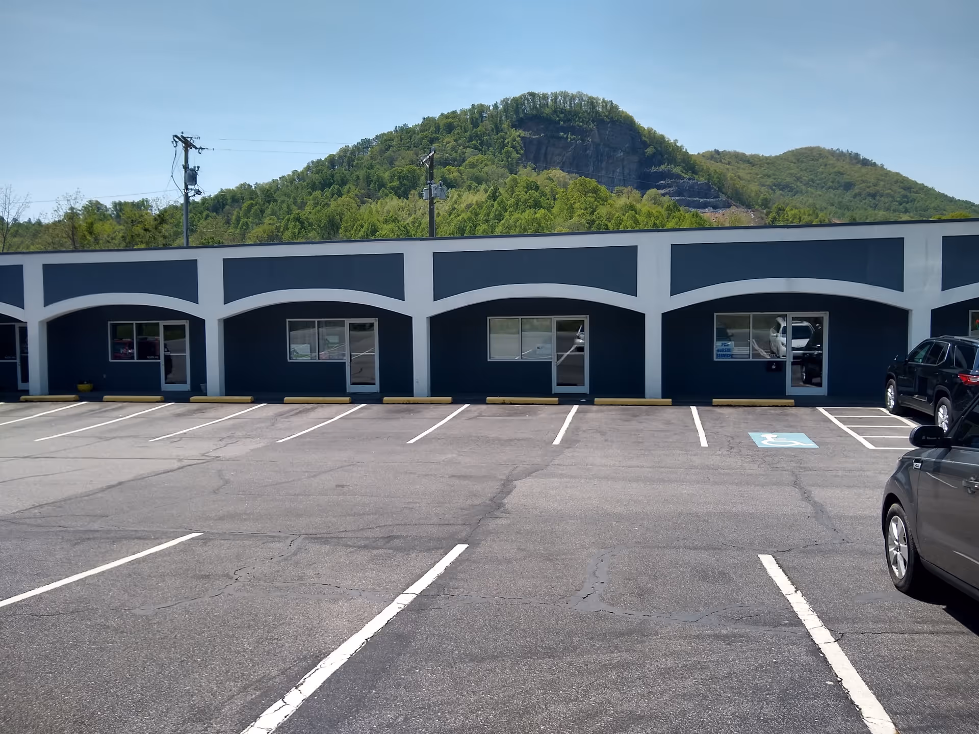 Blue single-story building with arched white trim and a spacious parking lot in front