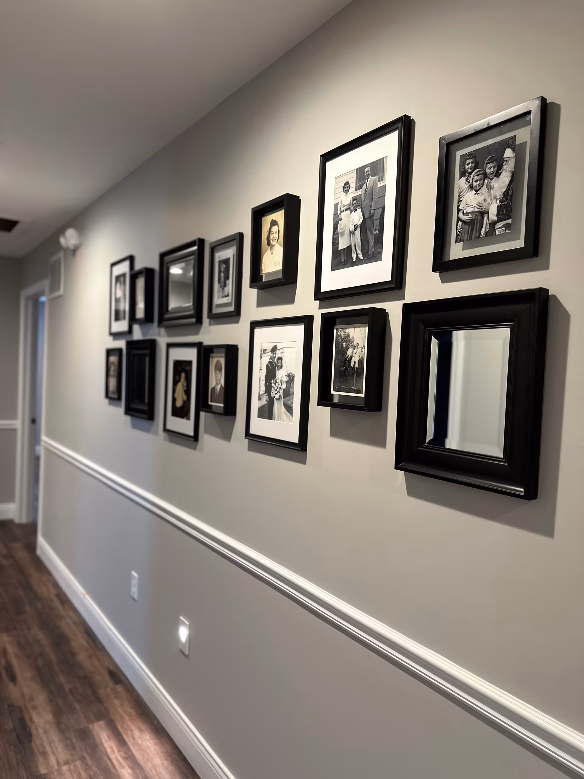 Long hallway with black-framed family photos along a gray wall.