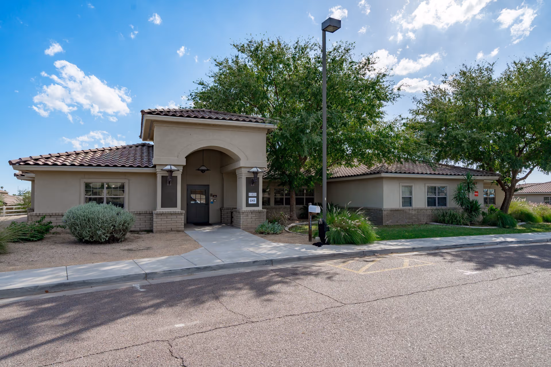 Single-story senior living facility with stucco walls, tiled roof, and landscaped entrance.
