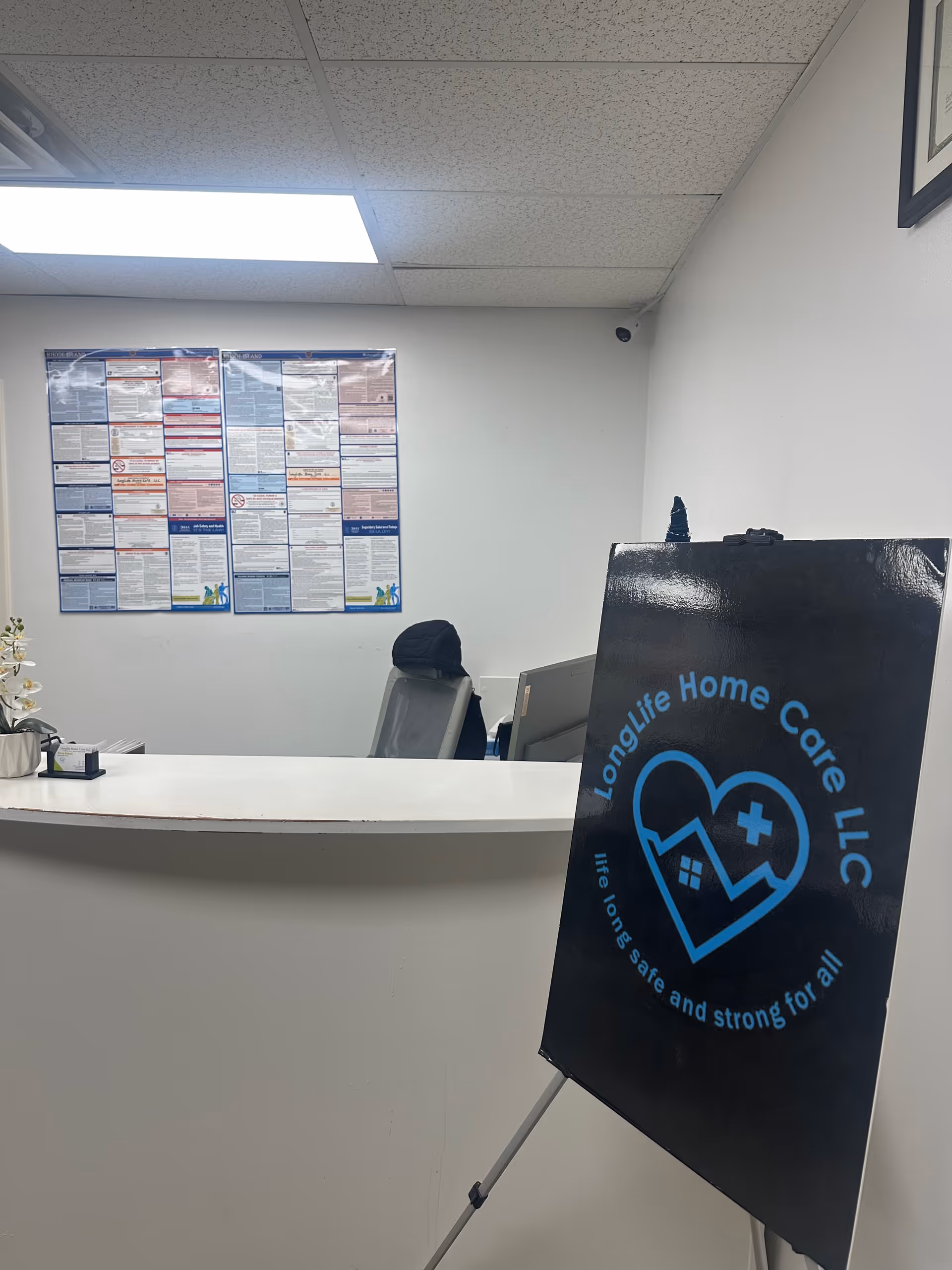 Reception desk in a clinical office with a LongLife Home Care LLC signboard.
