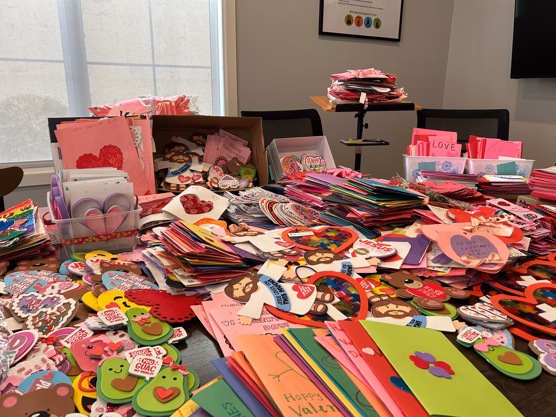 Table covered with handmade valentines and colorful craft cards in a senior living facility.