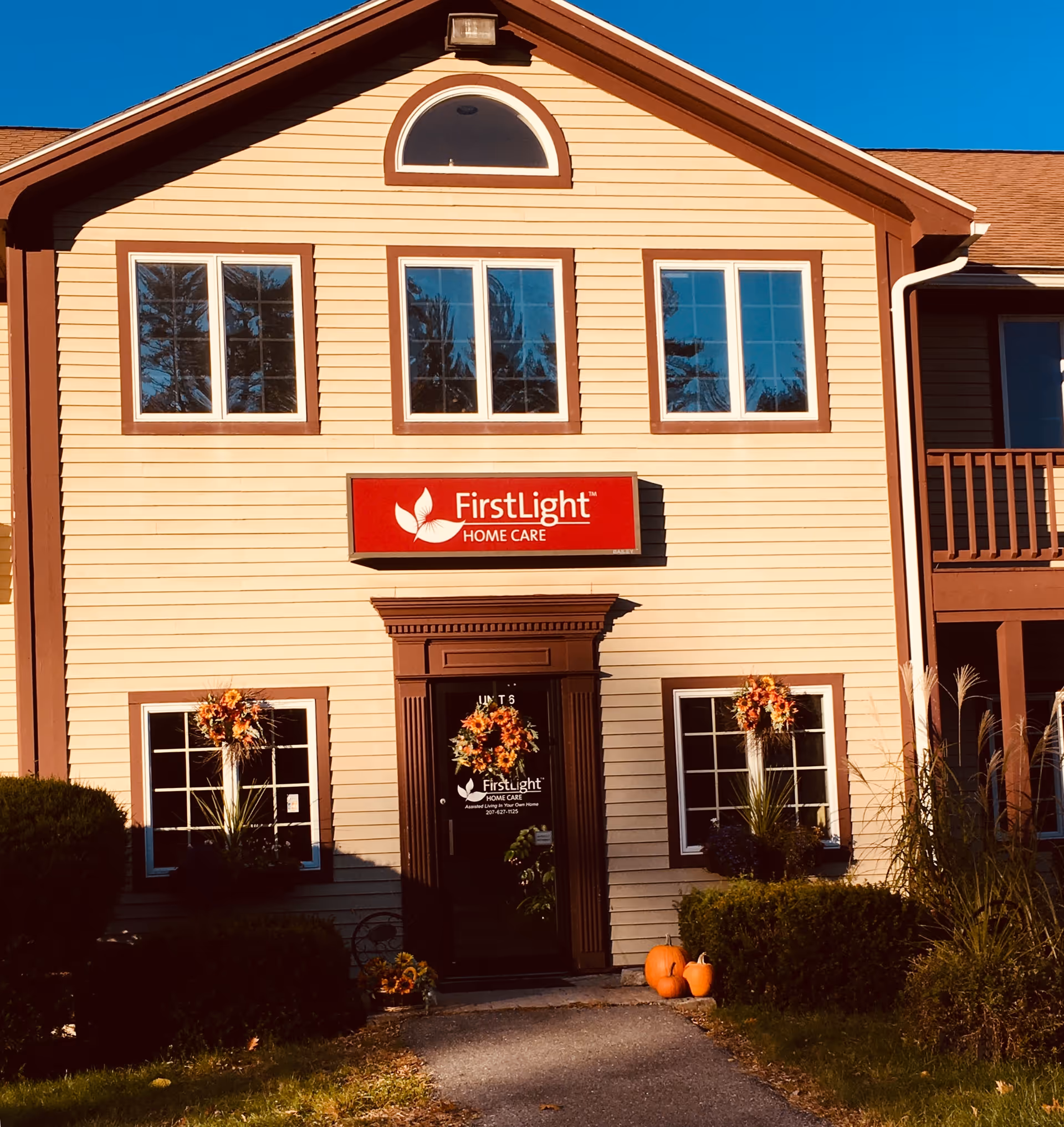 Front exterior of a FirstLight Home Care building with pumpkins at entrance.