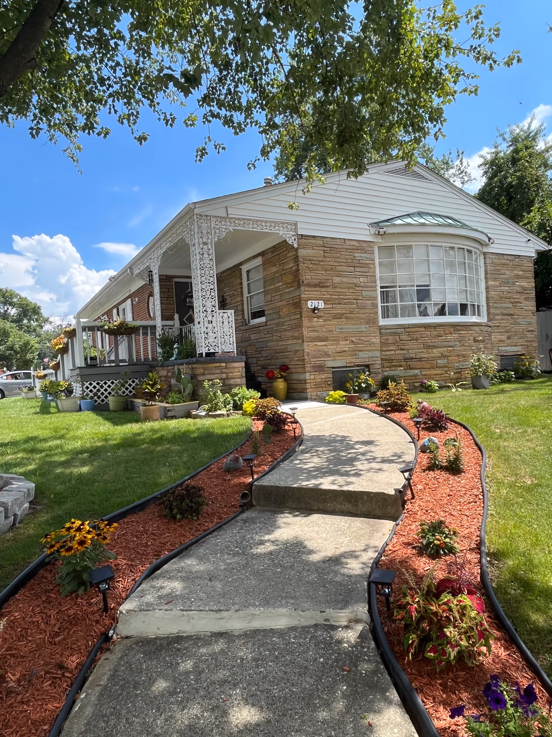 Exterior view of Jules Comfort Care LLC facility with a curved walkway and landscaped garden.