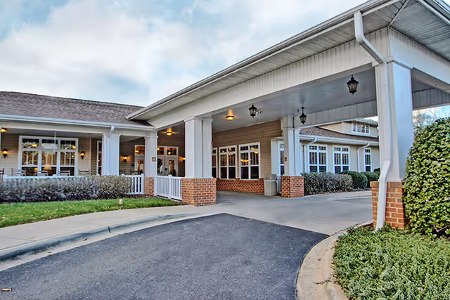 Exterior view of Evergreen Senior Living's covered entrance with brick pillars and driveway.