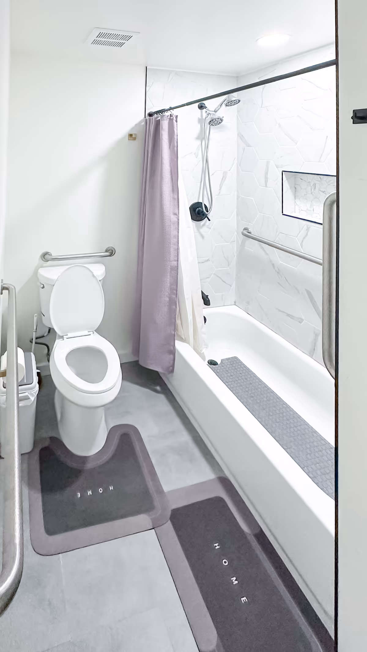 Accessible bathroom with toilet, walk-in bathtub, purple shower curtain, and safety grab bars.