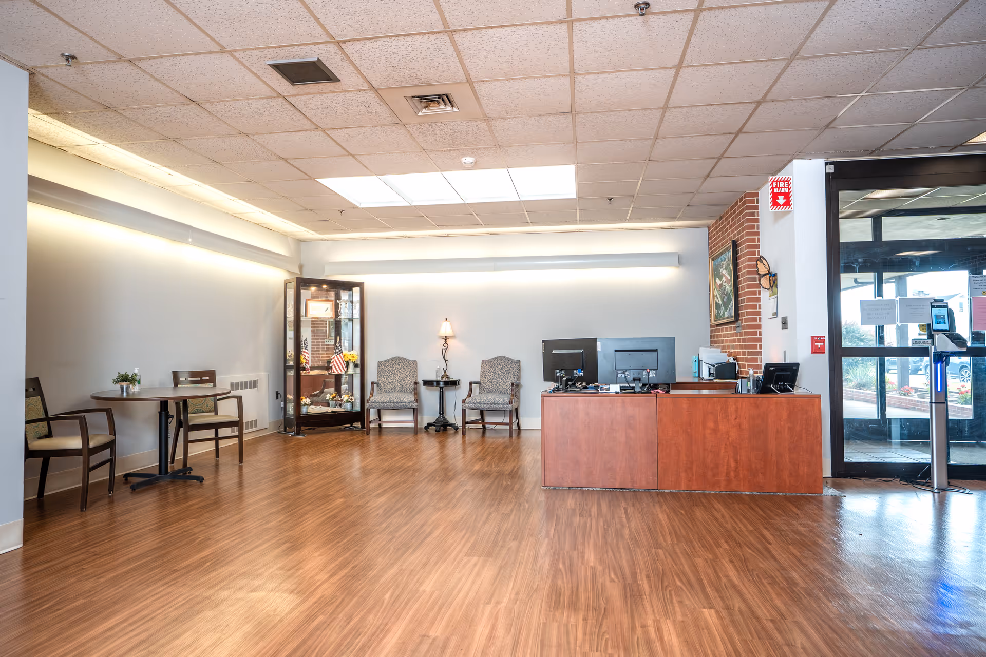 Empty senior living facility lobby with a reception desk, chairs, and a display cabinet.