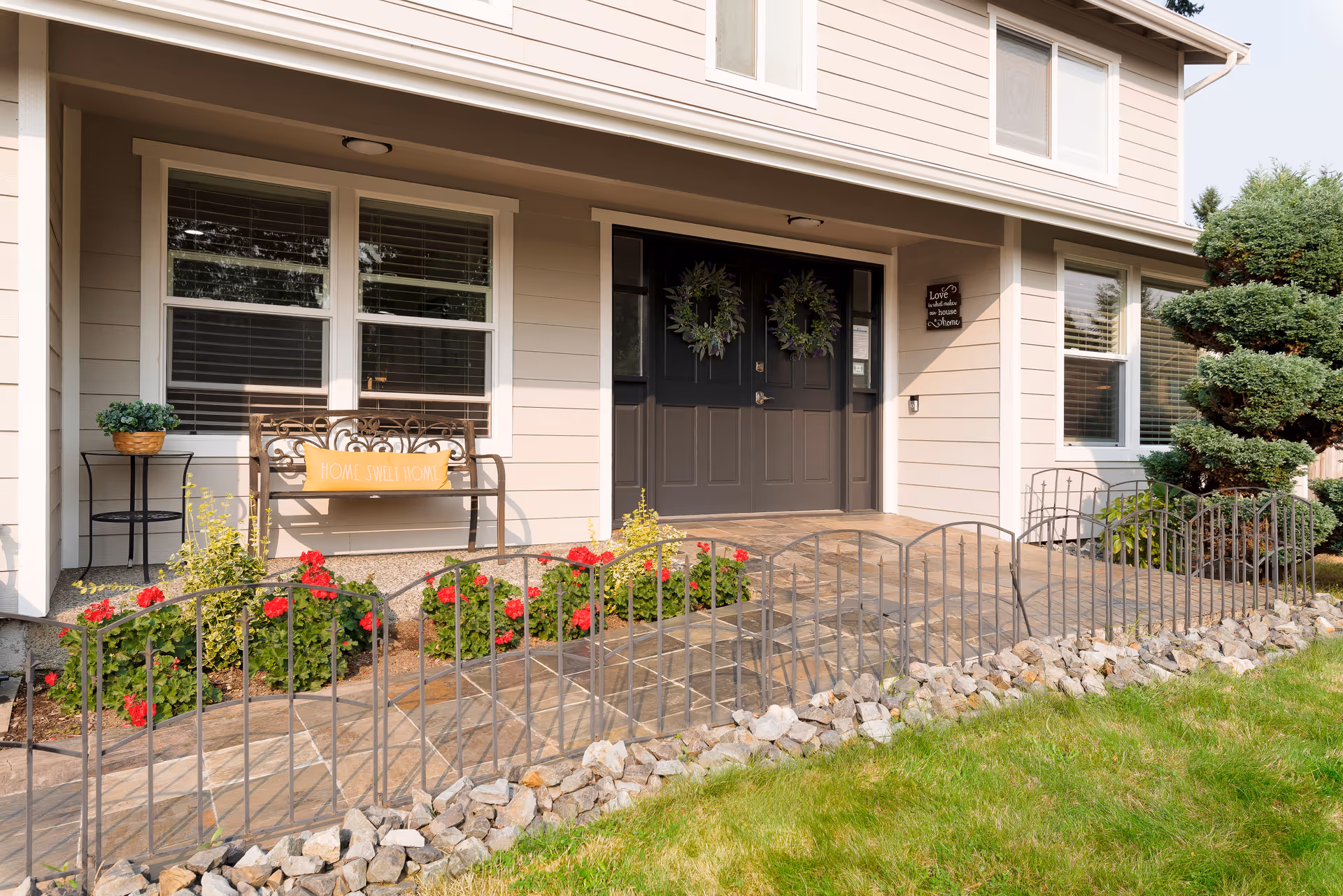 Exterior entrance of a senior living facility with double doors, wreaths, and landscaped front yard.