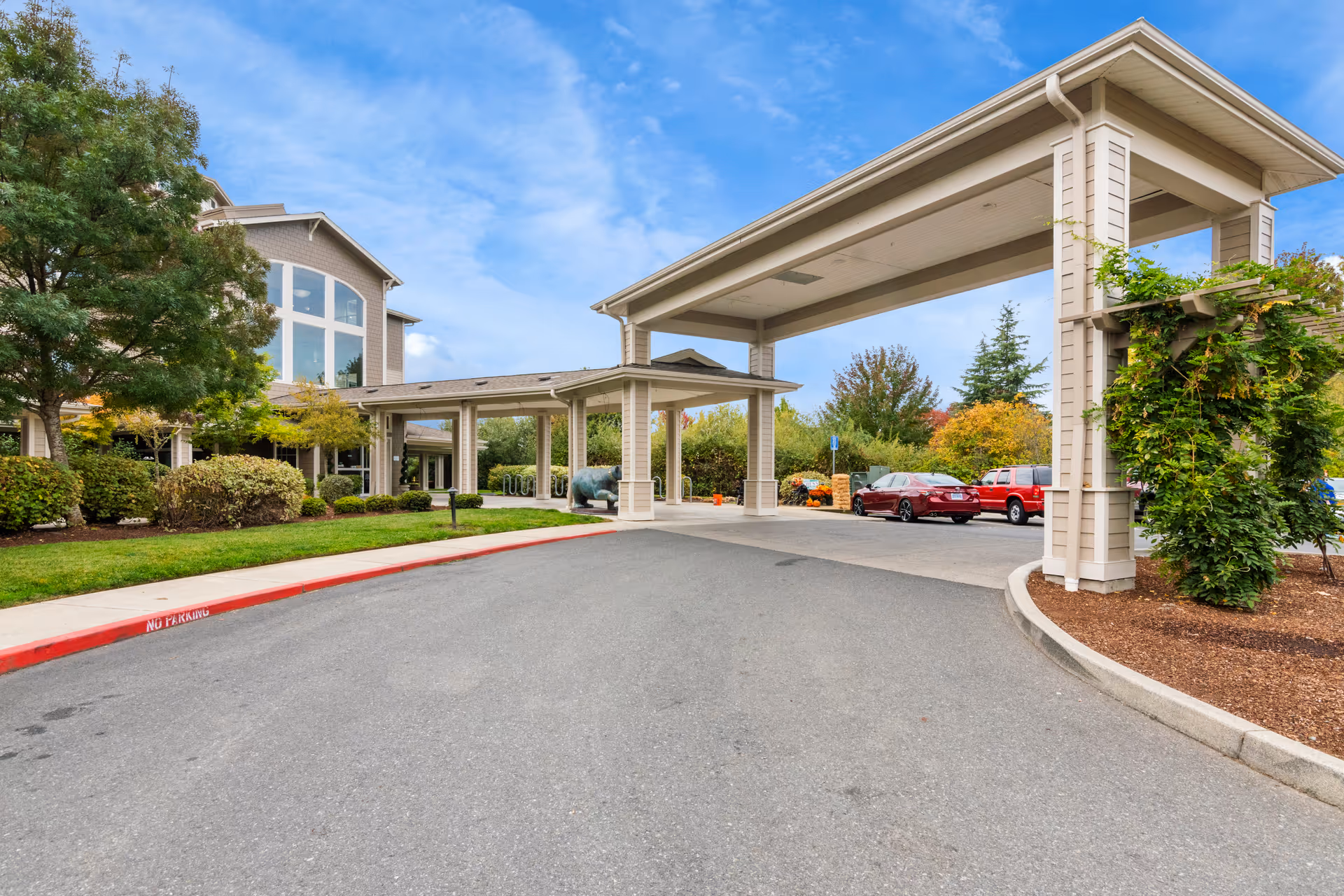 Exterior view of Cascades of Grants Pass entrance with a covered drop-off and parked cars.