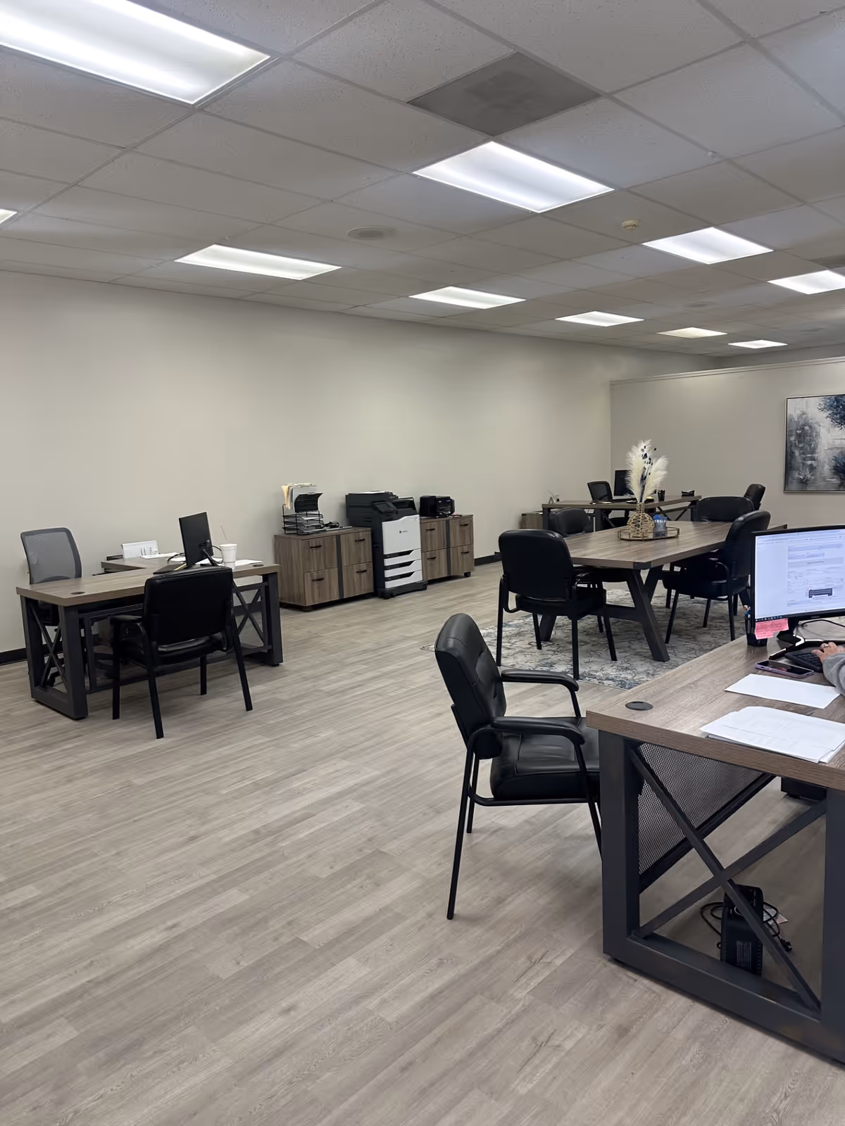 Empty office area with desks, chairs, printers, and filing cabinets in a senior living facility.