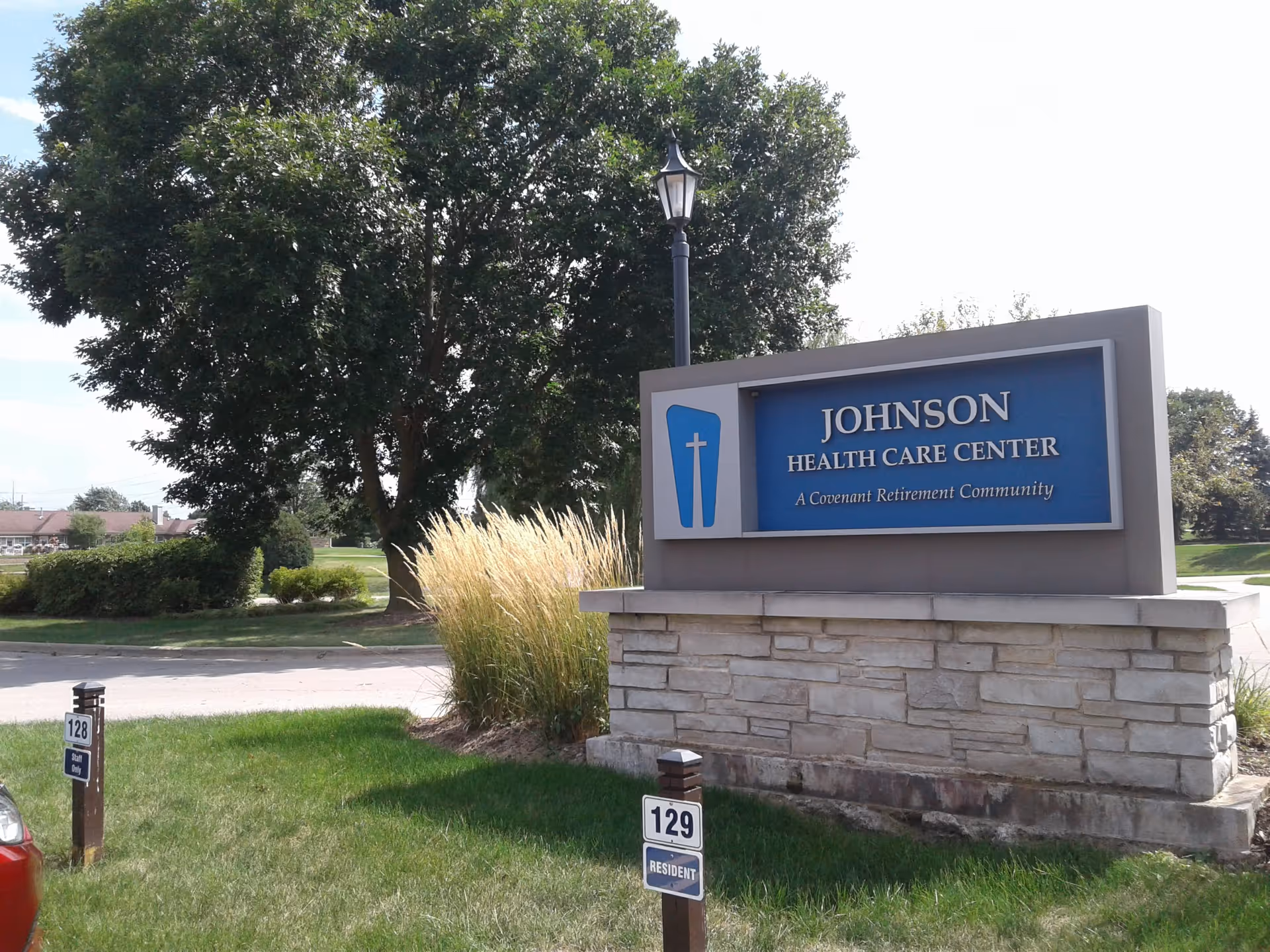 Exterior view of Johnson Health Care Center sign with lawn and trees