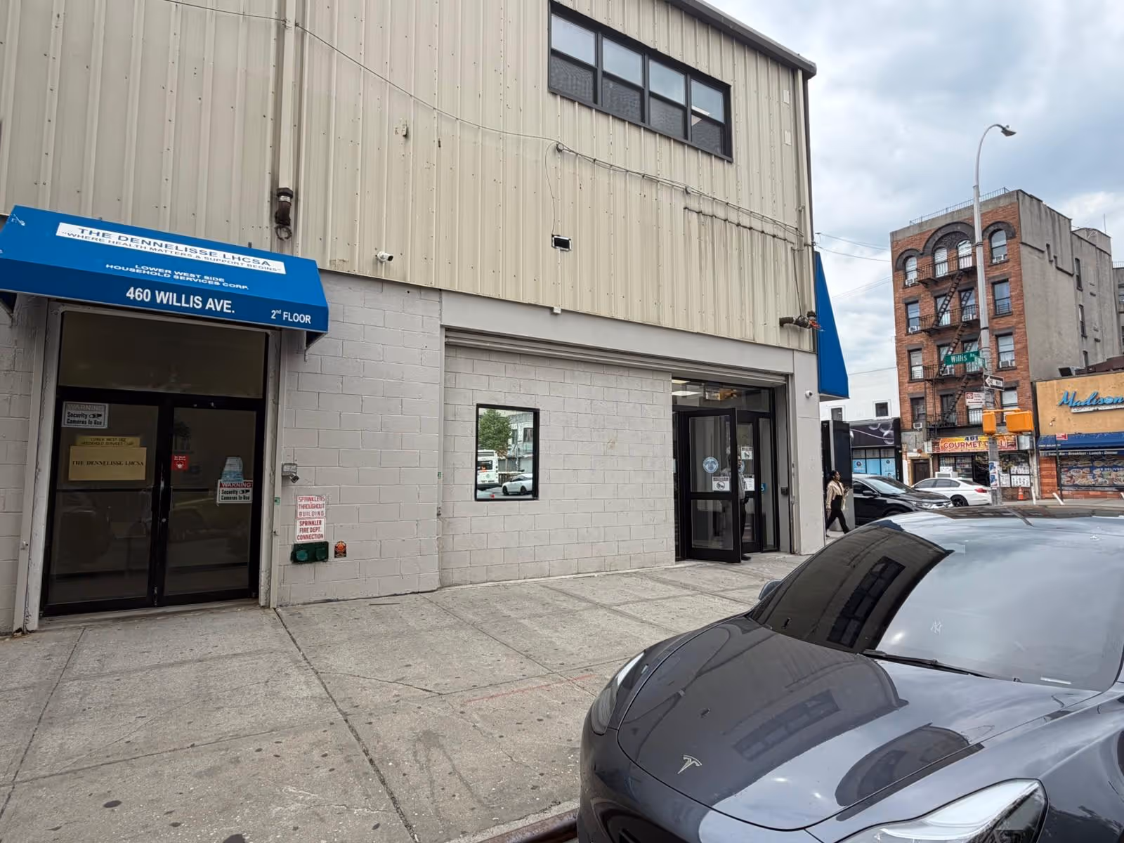 Exterior view of The Dennelisse LHCSA building with blue awning and glass doors.