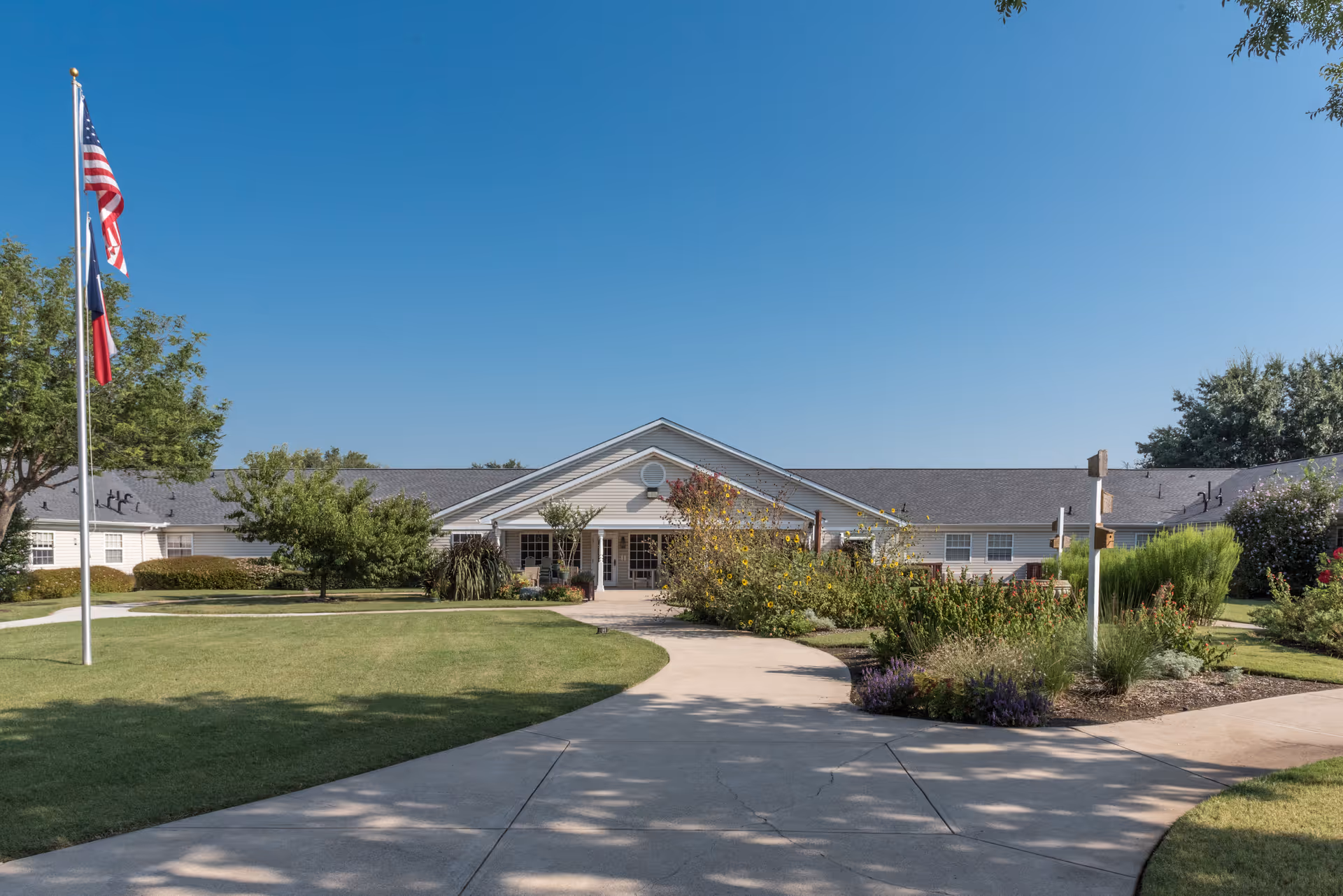Front view of Arden Courts of Richardson exterior with flags and manicured landscaping