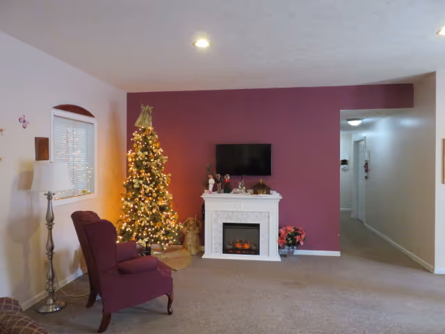 Cozy living room with a Christmas tree, purple accent wall, and fireplace mantel.